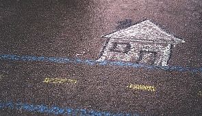 Räumlichkeiten - Das Bild zeigt ein mit Kreide auf die Straße gemaltes Haus.
